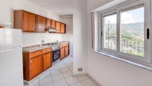 Una cocina con armarios de madera, una estufa y una ventana con vistas a la ciudad.