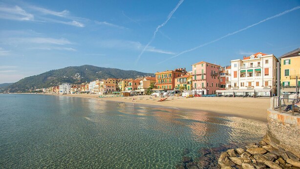 Un pueblo costero con aguas cristalinas, una playa de arena y edificios coloridos a lo largo de la costa.