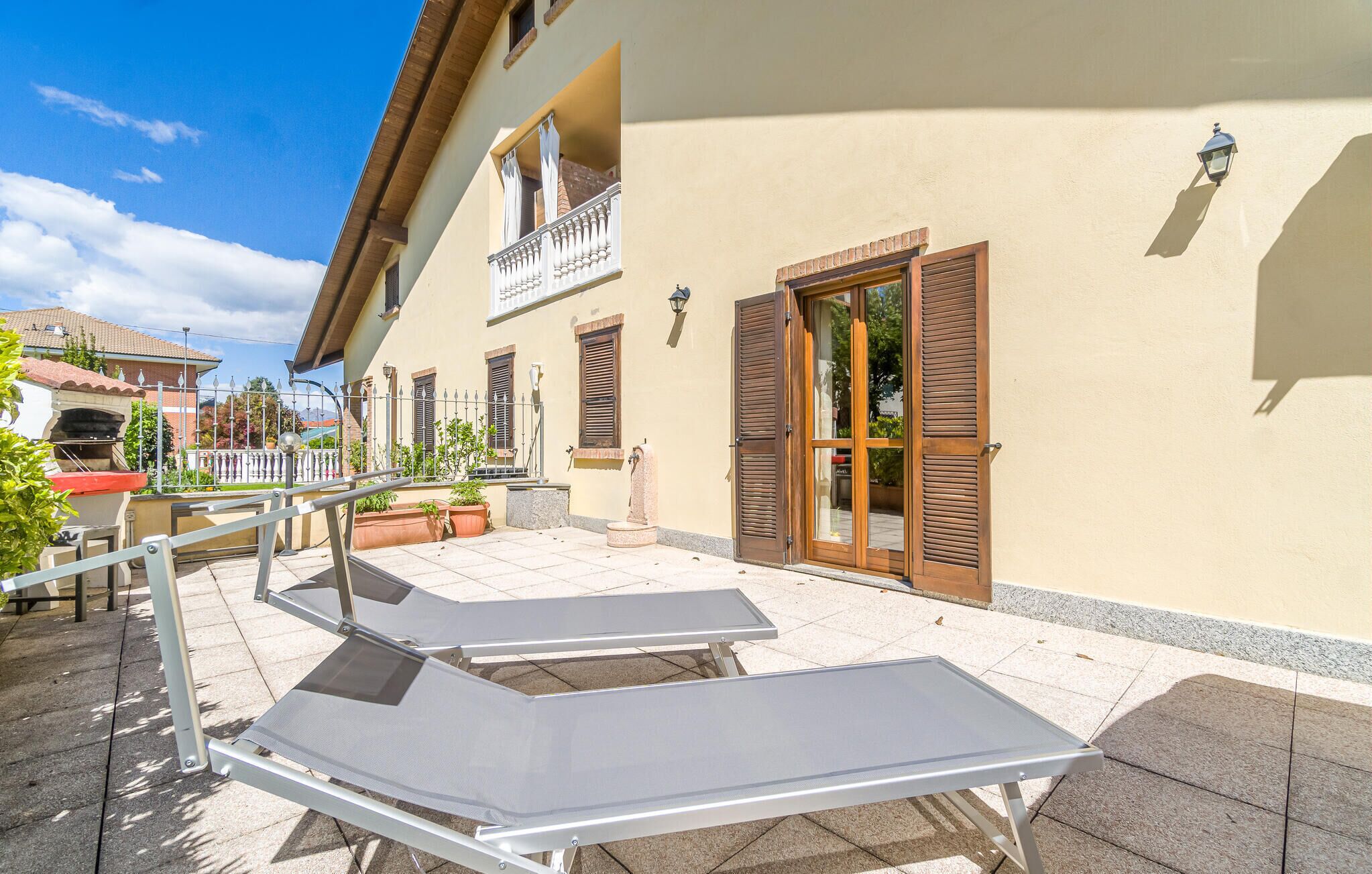 A building with a balcony, outdoor seating, and a door with shutters.
