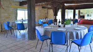 Un ristorante con sedie e tavoli blu, pareti in pietra e travi in legno.