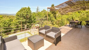 An outdoor patio with wicker furniture and a view of the surrounding greenery.