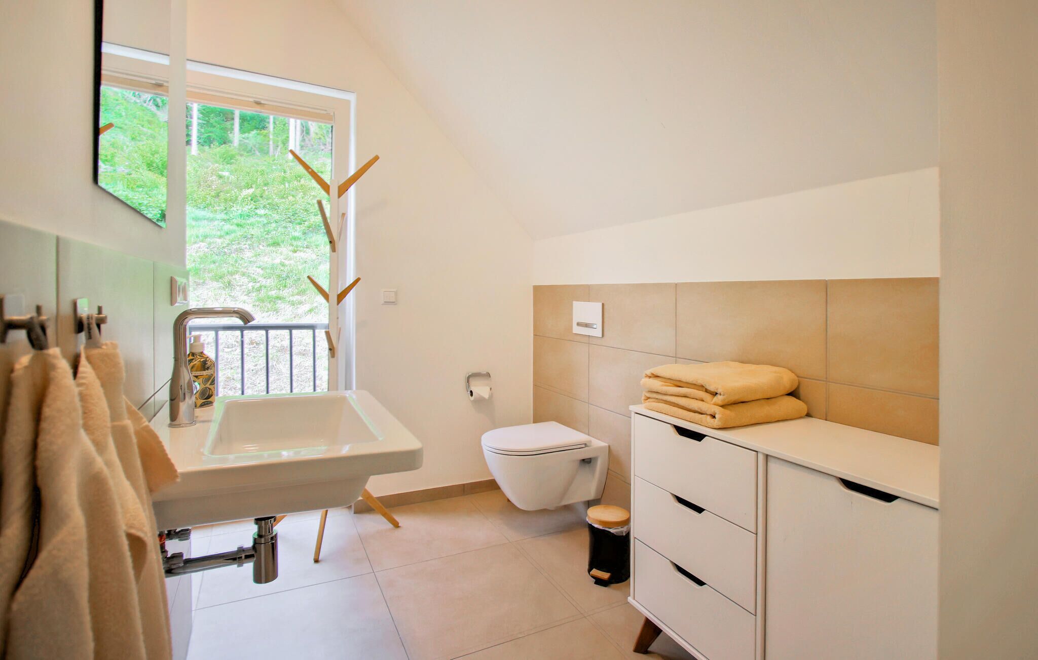 A modern bathroom with a sink, toilet, and storage cabinet.