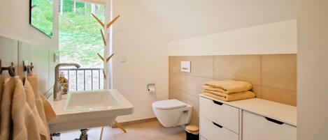 A modern bathroom with a sink, toilet, and storage cabinet.