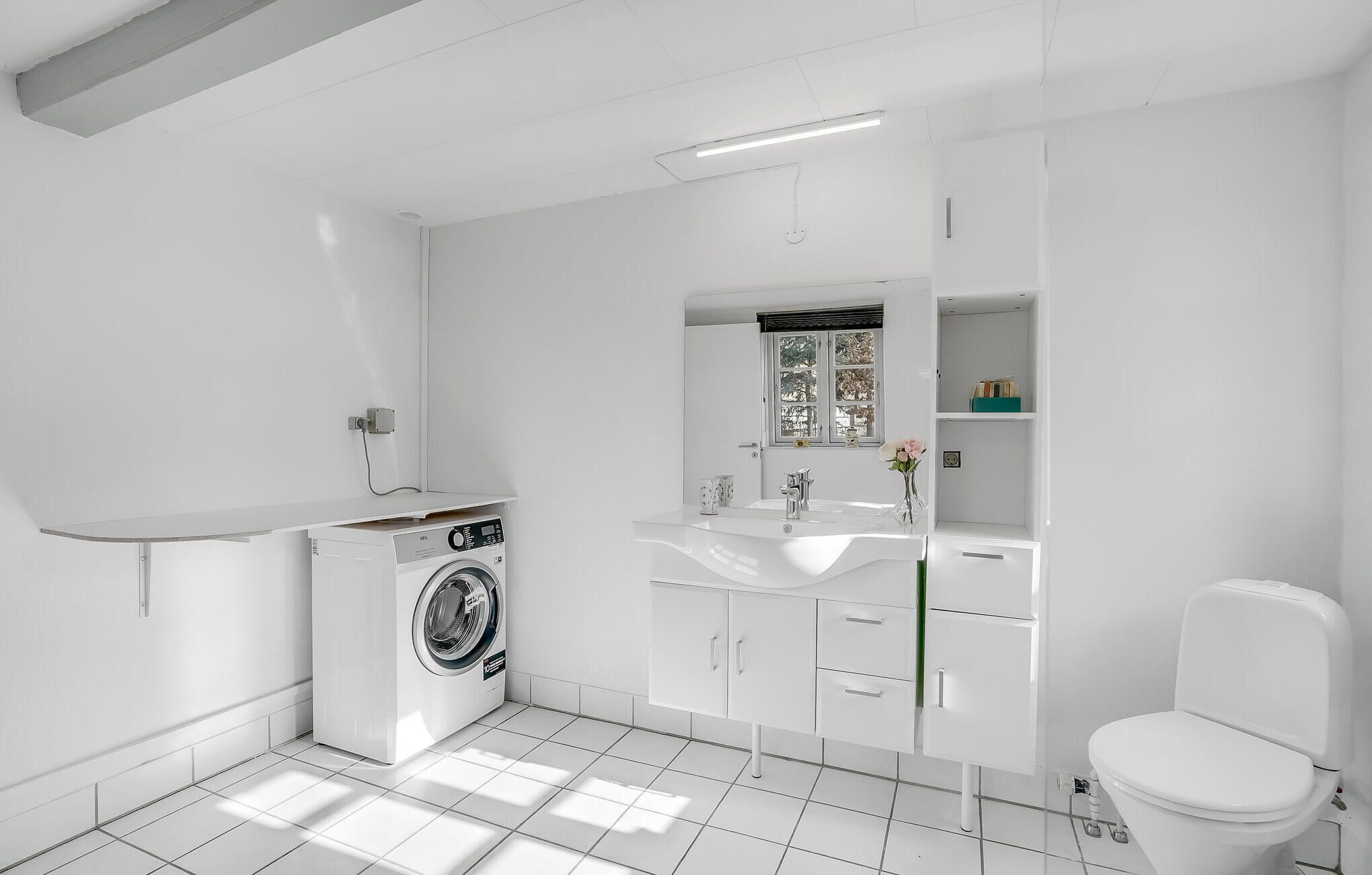 A modern bathroom with a washing machine, a sink, and a toilet.