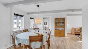 A dining area with a round table, wooden chairs, and a hanging light fixture. - Cozy home in Dannemare with WiFi (Dannemare)