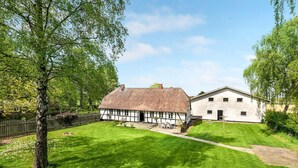 A traditional half-timbered house with a thatched roof and a white building with a gabled roof. - Cozy home in Dannemare with WiFi (Dannemare)