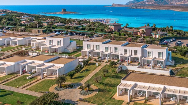 Une station balnéaire dotée de villas modernes, d’une plage et d’un château qui se profile à l’arrière-plan.