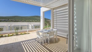 Un balcon avec une table et des chaises, une vue sur une colline et une balustrade blanche.