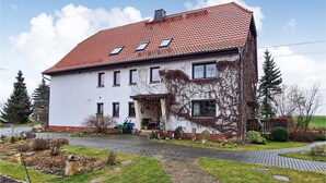 A two-story house with a red-tiled roof, a front porch, and a garden with a paved pathway. - Cozy apartment in Herrnhut OT Ruppersdor (Herrnhut)