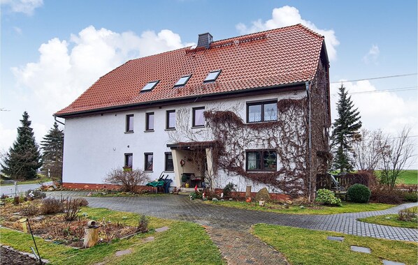 A two-story house with a red-tiled roof, a front porch, and a garden with a paved pathway. - Cozy apartment in Herrnhut OT Ruppersdor (Herrnhut OT Ruppersdor)