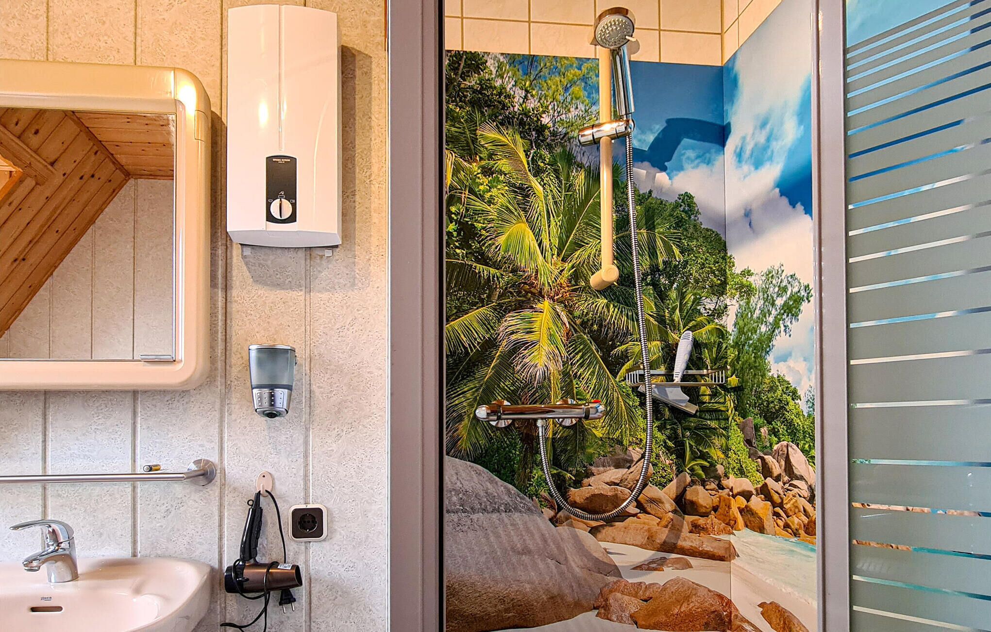 A bathroom with a modern sink, a towel rack, a shower with a rain showerhead, and a decorative mural of a tropical scene.