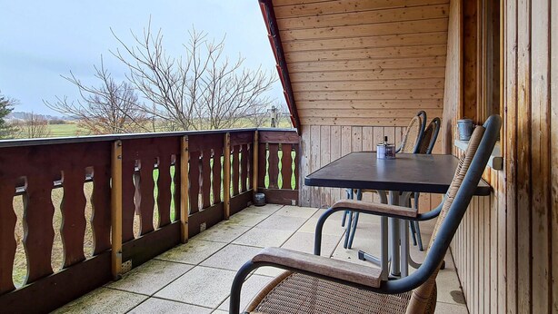 A wooden deck with a table and chairs, overlooking a grassy area with trees. - Cozy apartment in Herrnhut OT Ruppersdor (Herrnhut)