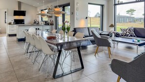 Una cucina moderna con zona pranzo, ampie finestre e vista sull'esterno.