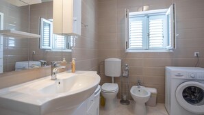 Un baño moderno con un lavamanos grande, inodoro, bidé y lavadora.