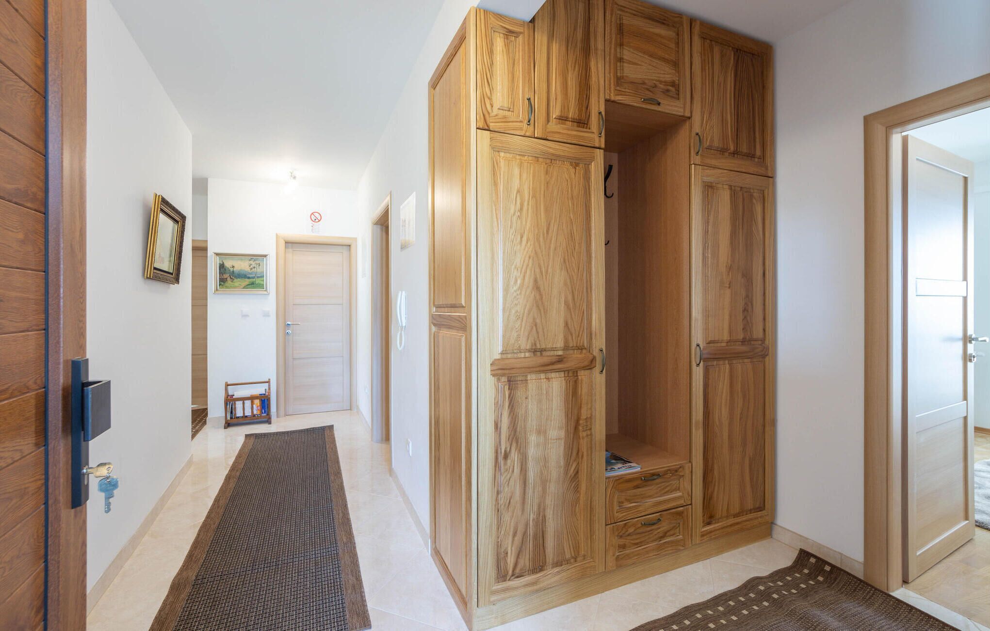 A hallway with wooden wardrobe units, a door with a no smoking sign, and a framed picture on the wall.