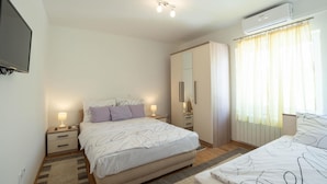 Un dormitorio moderno con cama, mesitas de noche, armario y aire acondicionado.