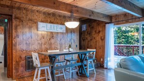 A wooden interior with a dining table, chairs, and a sign indicating a lake direction. - SNOW, SNOW & MORE SNOW AND SUGAR BEAR IS PLOWED! 12 MIN TO DODGE, 5 MIN TO SLED (Cold Springs)