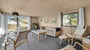 Una habitación acogedora con techo de madera, un sofá, dos sillones, una mesa y una chimenea.