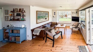 A living room with a wooden floor, a brown leather sofa, a blue cabinet, a painting, and a television. - Nice home in Hurup Thy with kitchen (Hurup Thy)