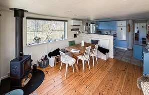 A modern kitchen with a central island, wooden flooring, and a large window with a view of trees.