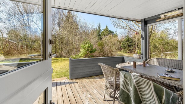 A covered patio with a table and chairs, a view of the surrounding trees, and a wooden deck. - Nice home in Hurup Thy with kitchen (Hurup Thy)