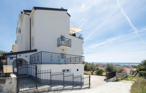 Un immeuble de deux étages doté d’un balcon et d’une entrée fermée par un portail.