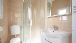 A bathroom with a toilet, a shower enclosure, and a sink with a mirror above it. - Nice apartment in Podstrana with WiFi (Podstrana)