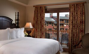 Relax in this stylish room with a large bed, nightstand, and glass door leading to a balcony with a view.