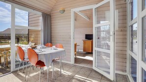 A sunlit room with a table set for dining, a television, and a sliding glass door leading outside. - Awesome home in Hadsund with WiFi (Hadsund)