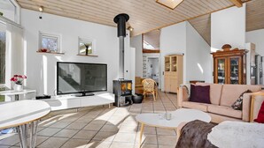 Un amplio salón con una televisión grande, chimenea, sofá y comedor.