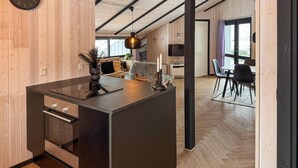 Une cuisine moderne dotée d’un îlot central, de murs en bois et d’un coin repas avec une table et des chaises.