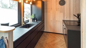 Une cuisine moderne avec une grande fenêtre, un plancher en bois et une horloge au mur.