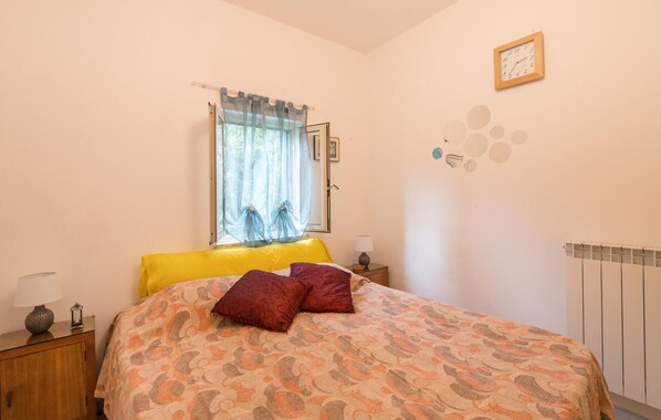 Une chambre à coucher avec un lit, une fenêtre avec des rideaux, une table de chevet, une lampe et une horloge murale.
