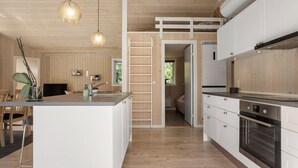 A modern kitchen with wooden paneling, a central island with a sink, and built-in appliances. - 3 bedroom beautiful home in Glesborg (Glesborg)