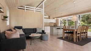 A modern interior with a wooden ceiling, a sofa, a dining table with chairs, and a kitchen area. - 3 bedroom beautiful home in Glesborg (Glesborg)