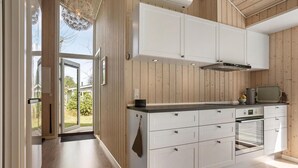 A modern kitchen with white cabinets, a black countertop, and a built-in oven. - 3 bedroom beautiful home in Glesborg (Glesborg)