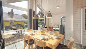 A dining area with a wooden table set for four, surrounded by chairs with cushions. There are hanging pendant lights above the table. - Cozy home in Krems II/Warderbrück with sauna (Krems II/Warderbrück)
