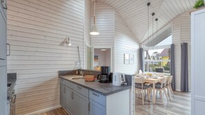 A modern kitchen with wooden paneling, a central island, and a dining area with a view. - Cozy home in Krems II/Warderbrück with sauna (Krems II/Warderbrück)