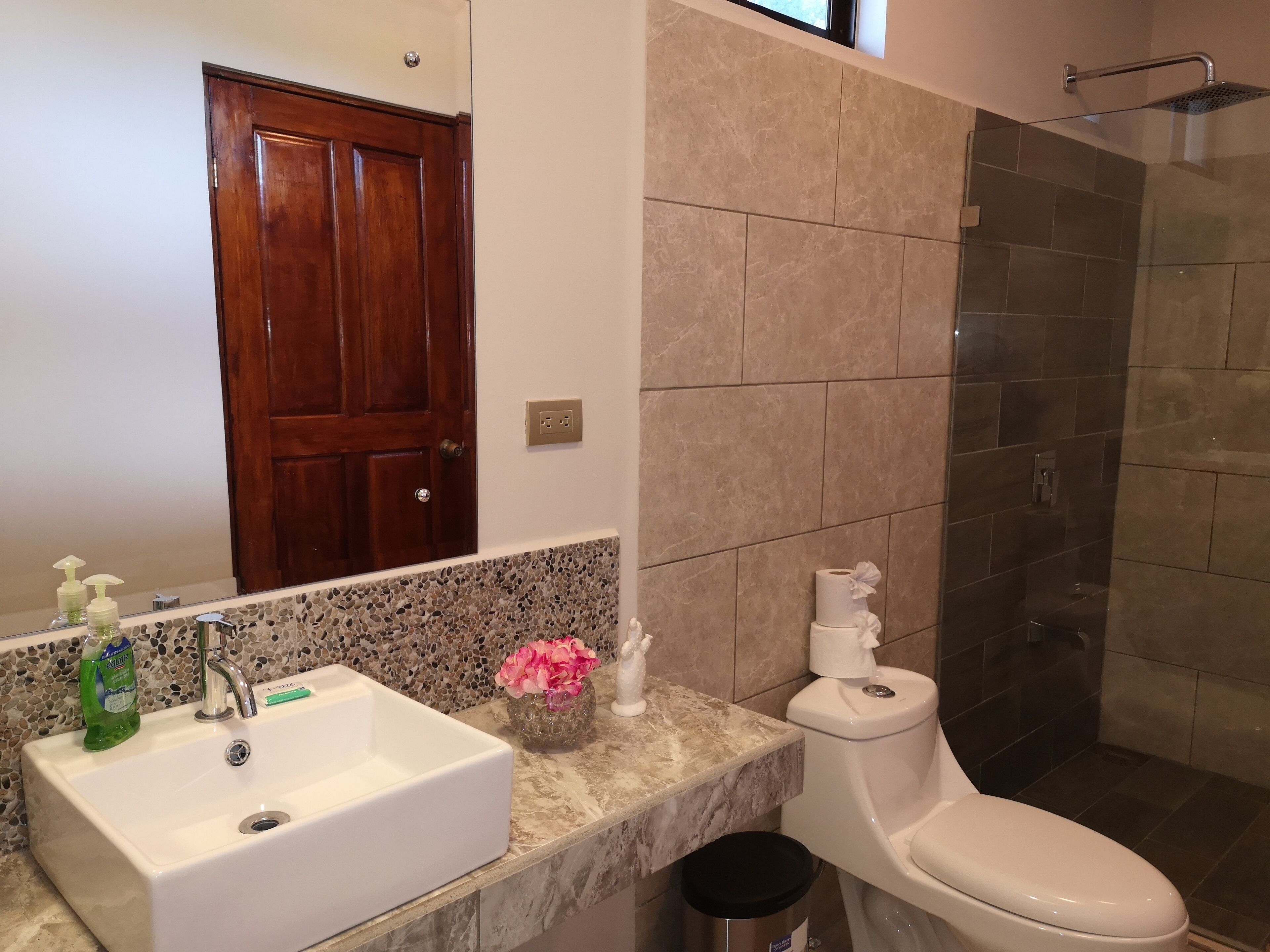A bathroom with a white sink, a toilet, and a shower area.