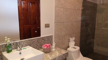A bathroom with a white sink, a toilet, and a shower area.