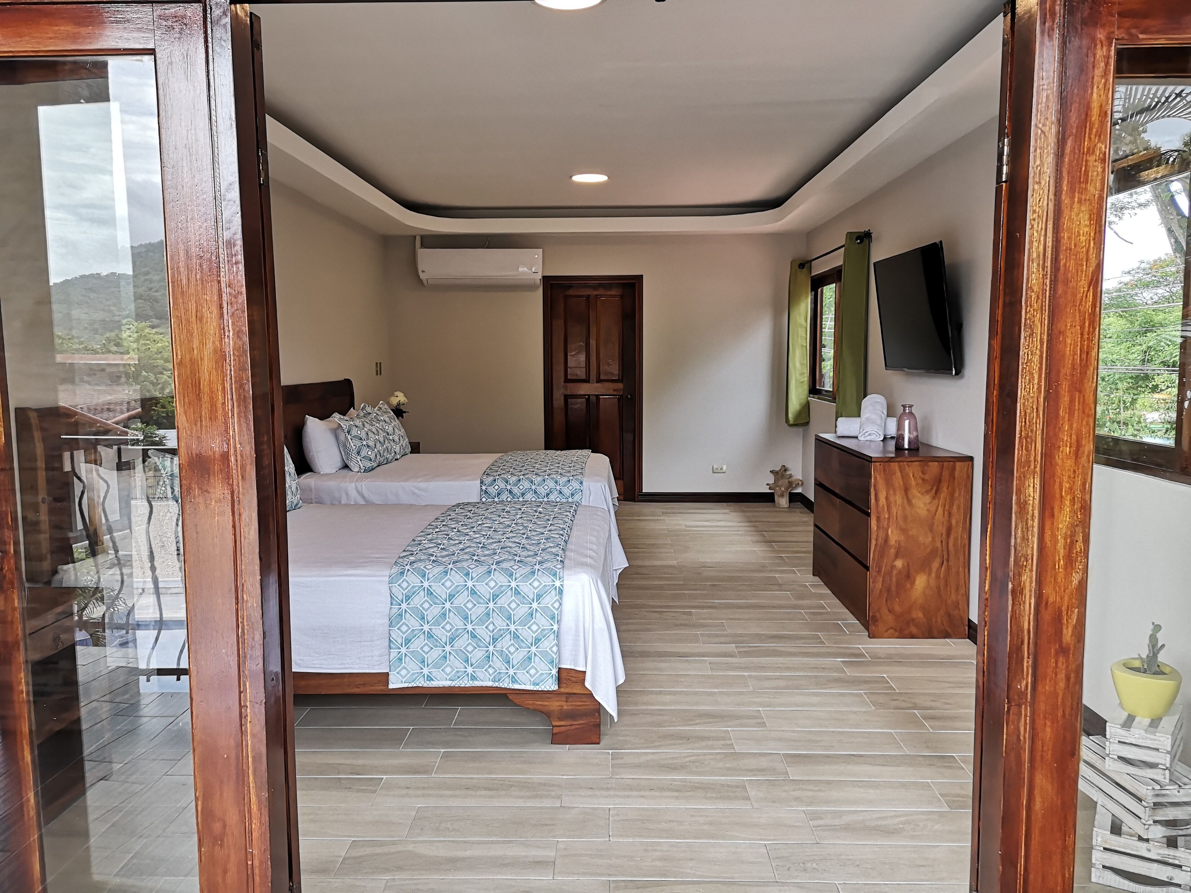 Un dormitorio con cama, mesita de noche, cómoda, televisor y aire acondicionado.