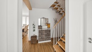 A modern interior with a wooden staircase, a white wall with a mirror, and a wooden floor. - Beautiful home in Süssau/Ostsee with sauna (Süssau/Ostsee)