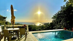 A wooden deck with a pool, lounge chairs, and a table with chairs. - Luxury Ocean View Villa in West Bay Roatan. 3 Bedrooms with Pool & Beach Access (Roatan)