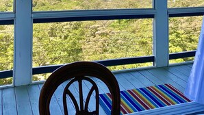 A room with a large window overlooking a coastal landscape with boats and greenery. - Luxury Ocean View Villa in West Bay Roatan. 3 Bedrooms with Pool & Beach Access (Roatan)