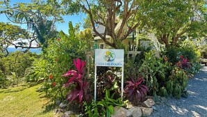 A sign for Casa Del Delfin surrounded by lush greenery and a clear view of the ocean. - Luxury Ocean View Villa in West Bay Roatan. 3 Bedrooms with Pool & Beach Access (Roatan)