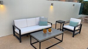 A white sofa with black metal frames, two matching chairs, a small table, and decorative pillows. - Vamos a la playa, private pool/central AC (Vega Alta)