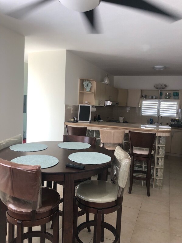 A dining area with a round table, chairs, and a kitchen in the background. - Vamos a la playa, private pool/central AC (Vega Alta)