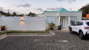 A modern house with a white exterior, a teal roof, and a white garage door. A white SUV is parked in the driveway. - Vamos a la playa, private pool/central AC (Vega Alta)