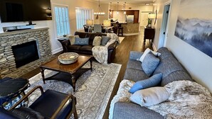 Ein geräumiges Wohnzimmer mit Kamin aus Stein, Ledersofas und einem großen Flachbildfernseher.