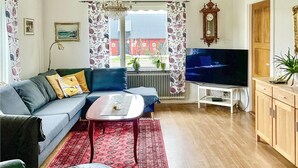 Een woonkamer met een bank, een salontafel, een televisie en een houten kast.